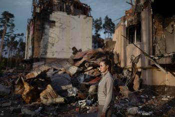A young Ukrainian woman walks amidst the ruins of her grandparents’ home in Irpin.