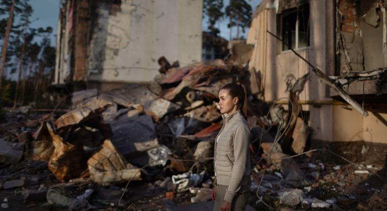 यूक्रेन में युद्ध से हुई तबाही के एक स्थल से गुज़रती हुई एक महिला.