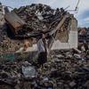 एक यूक्रेनी लड़की ज़ाइटॉमिर में अपने नष्ट स्कूल के मलबे में खड़ी है