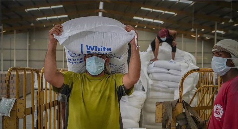 عامل في مستودع لبرنامج الأغذية العالمي في صنعاء يفرغ أكياس المساعدات الإنسانية.