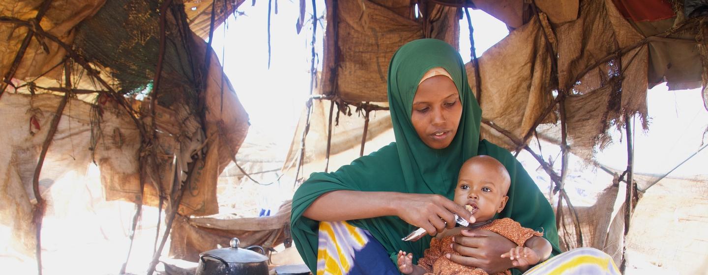 Un travailleur de santé de l'UNICEF donne de la nourriture thérapeutique à un bébé malnutri au centre OTP de Kabasa à Dollow, en Somalie.