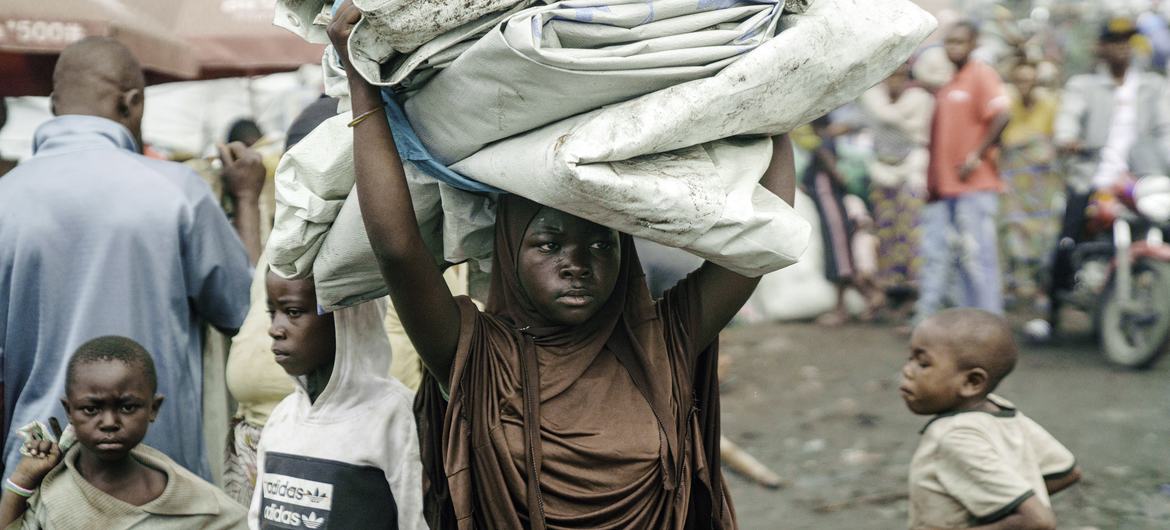 Una niña que había estado viviendo en campos de desplazados en los alrededores de Goma, lleva su tienda de campaña sobre la cabeza mientras busca refugio de camino a la aldea de Shasha, en la provincia de Kivu del Norte, RD del Congo, el 14 de febrero de…