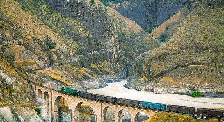 A train crosses a bridge as it makes its journey through a mountainous region.