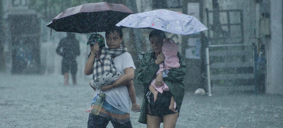 Parents carry their children as they walk on a flooded street in Quezon City, Philippines.