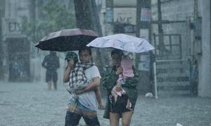 Parents carry their children as they walk on a flooded street in Quezon City, Philippines.