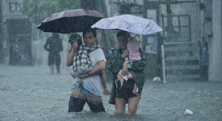 Parents carry their children as they walk on a flooded street in Quezon City, Philippines.