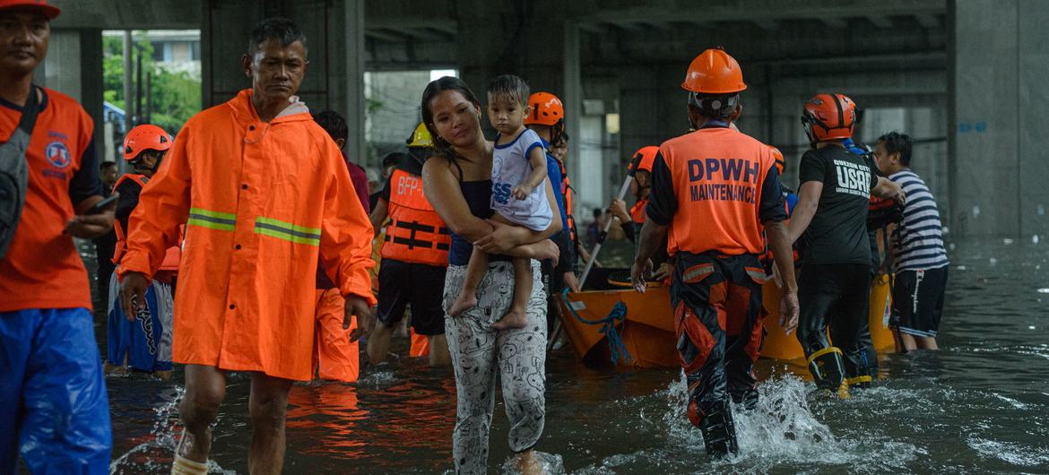 Los trabajadores de respuesta a desastres y de rescate evacúan a niños y sus familias de sus hogares inundados en Ciudad Quezón, Filipinas.