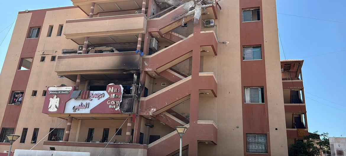 صورة خارجية متضررة لمجمع ناصر الطبي في غزة، تُظهر مبنى متعدد الطوابق مع درج منهار وأنقاض.