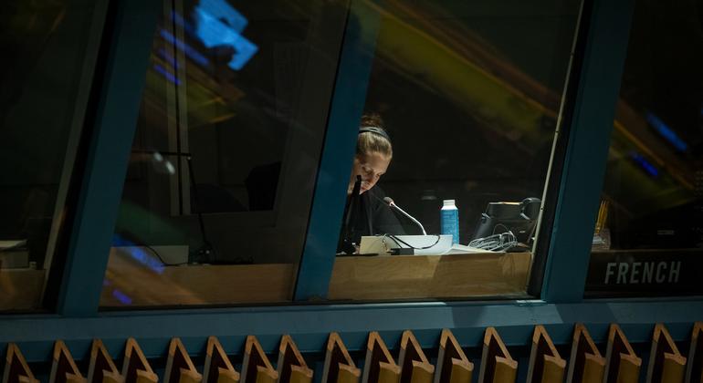 Uma intérprete trabalhando em uma cabine com vista para o Salão da Assembleia Geral no quarto dia do 78º Debate da Assembleia Geral