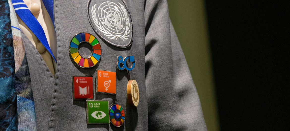 Um paletó cinza com vários pins das Nações Unidas , incluindo o emblema da ONU e pins dos ODS (Objetivos de Desenvolvimento Sustentável), usado na 80ª Assembleia Geral da ONU .