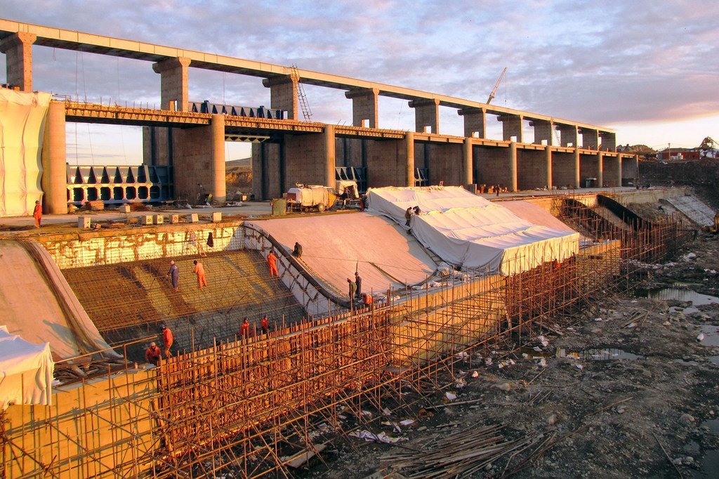 Construcción de la presa de Intumak en el río Nura, en Kazajstán, mostrando a los trabajadores y los andamios en la estructura de la presa.