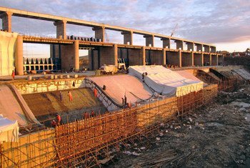 哈萨克斯坦努拉河上的因图马克大坝正在建设中，图中可见工人在大坝结构上作业和搭建脚手架。