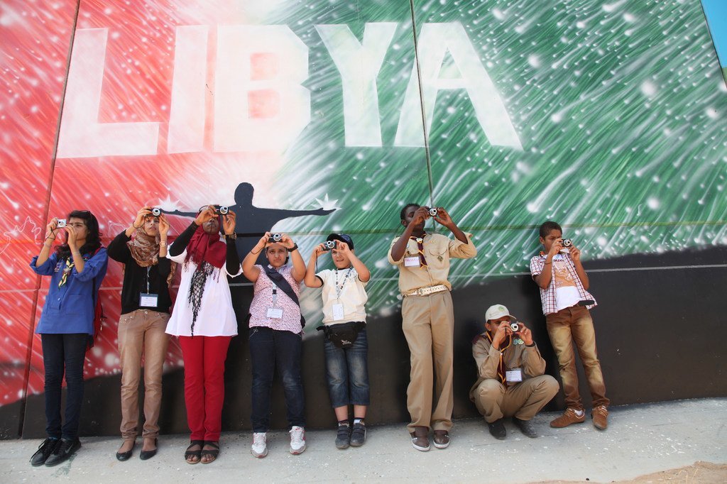 فتيات الكشافة الليبيات يشاركن في ورشة عمل تصوير الأطفال التي UNICEF في طرابلس، حيث قمن بتصوير جدارية مكتوب عليها "ليبيا".