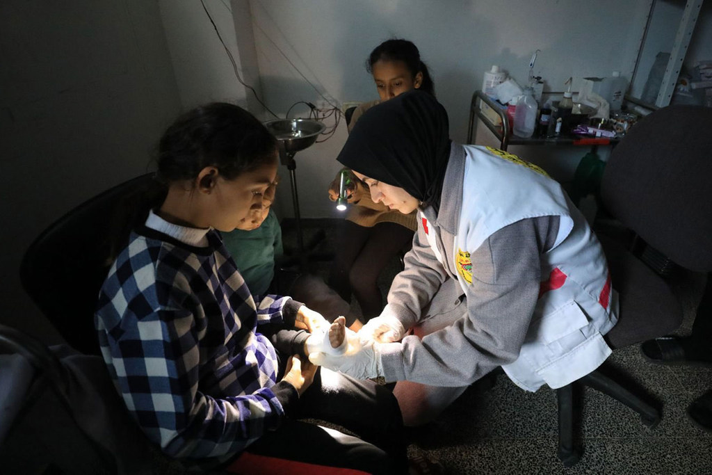Una trabajadora sanitaria venda el pie de un niño en un hospital de Gaza.