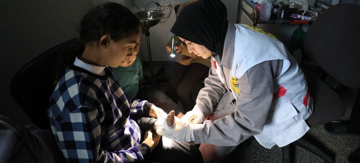 Una trabajadora sanitaria venda el pie de un niño en un hospital de Gaza.