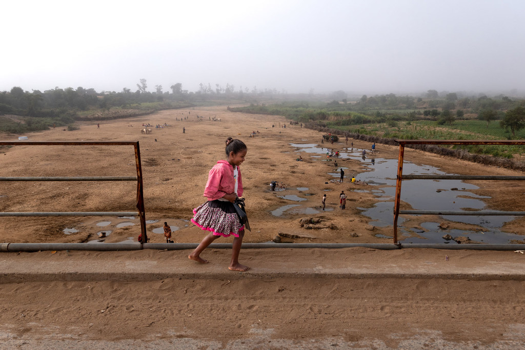 Девочка переходит через мост над высохшей рекой в Индии. 