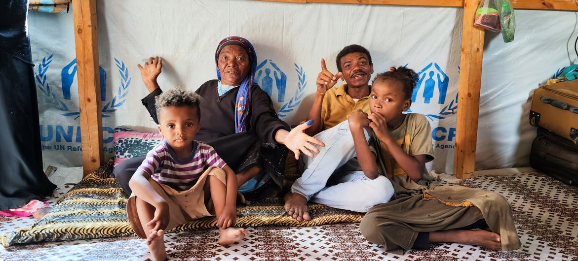 A family sit in their shelter at a displaced persons site in Aden, Yemen.