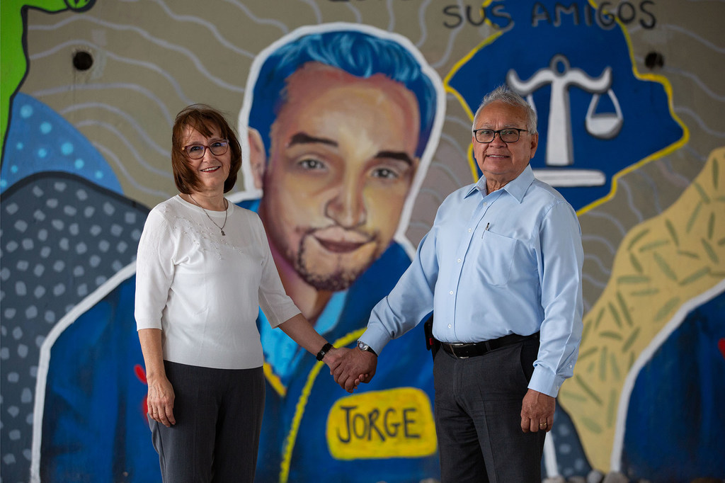 Rosy Mercado y Joel Medina posan frente a un mural que representa a Jorge, el hijo asesinado de ella.