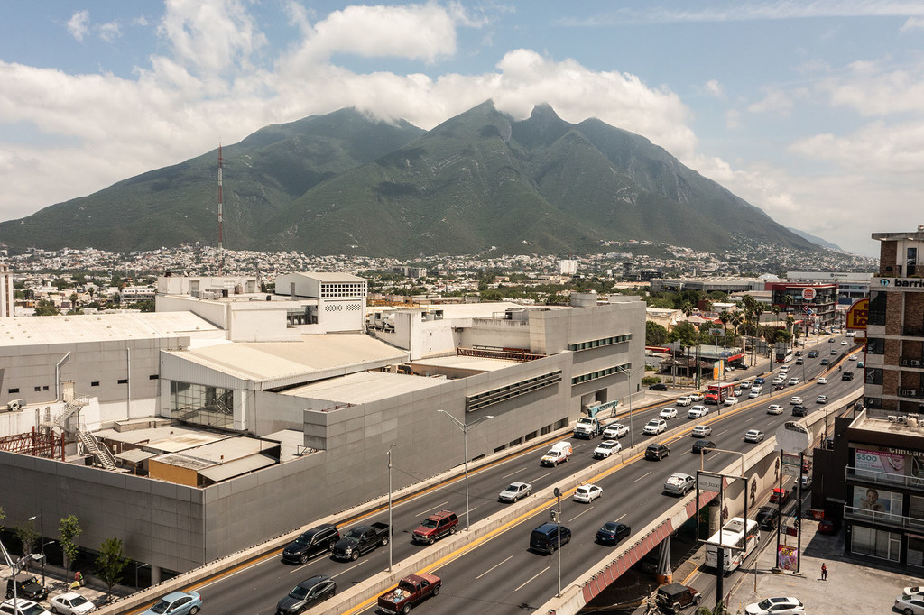 Vista de Monterrey, Nuevo León, México, con una carretera en primer plano y una gran montaña al fondo.