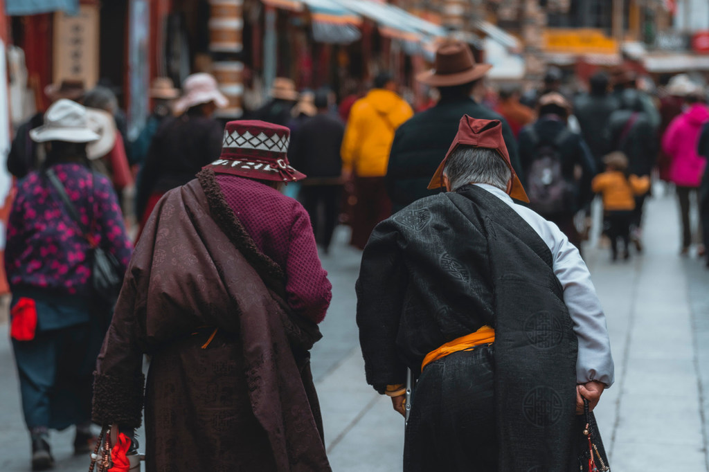 Dos personas mayores tibetanas caminan hacia un acto religioso en Lhasa.