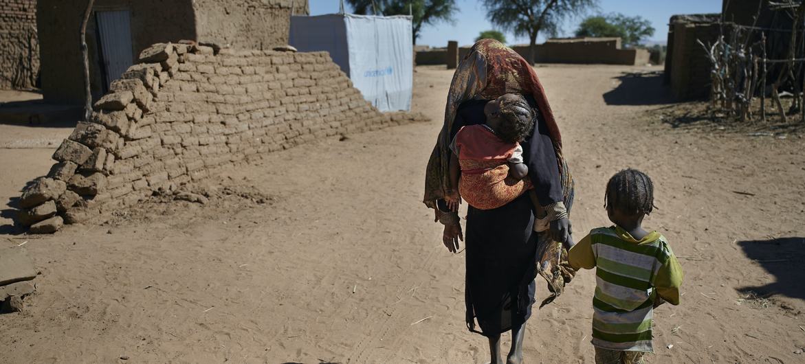 نازحة مع أطفالها في طريقهم مخيم للنازحين بالقرب من الفاشر، عاصمة شمال دارفور.