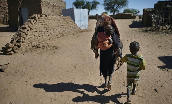 نازحة مع أطفالها في طريقهم مخيم للنازحين بالقرب من الفاشر، عاصمة شمال دارفور.