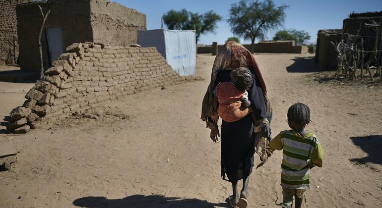 Crianças caminhando para seu abrigo em um campo de deslocados internos perto de El Fasher, capital do Norte de Darfur, Sudão