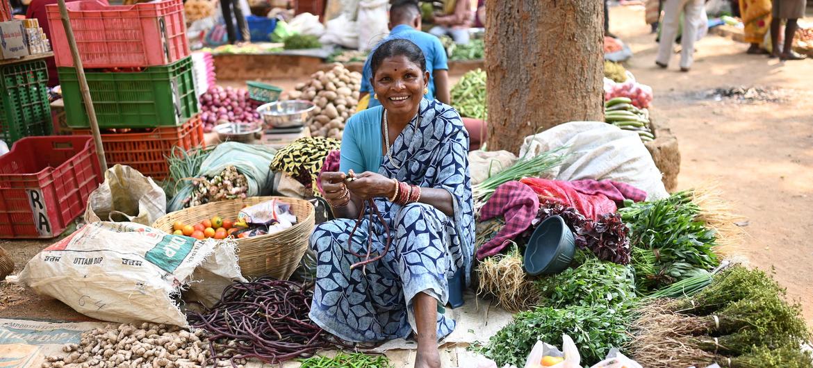 Seorang wanita dari komunitas suku yang menjual hasil hutan di pasar lokal di India.