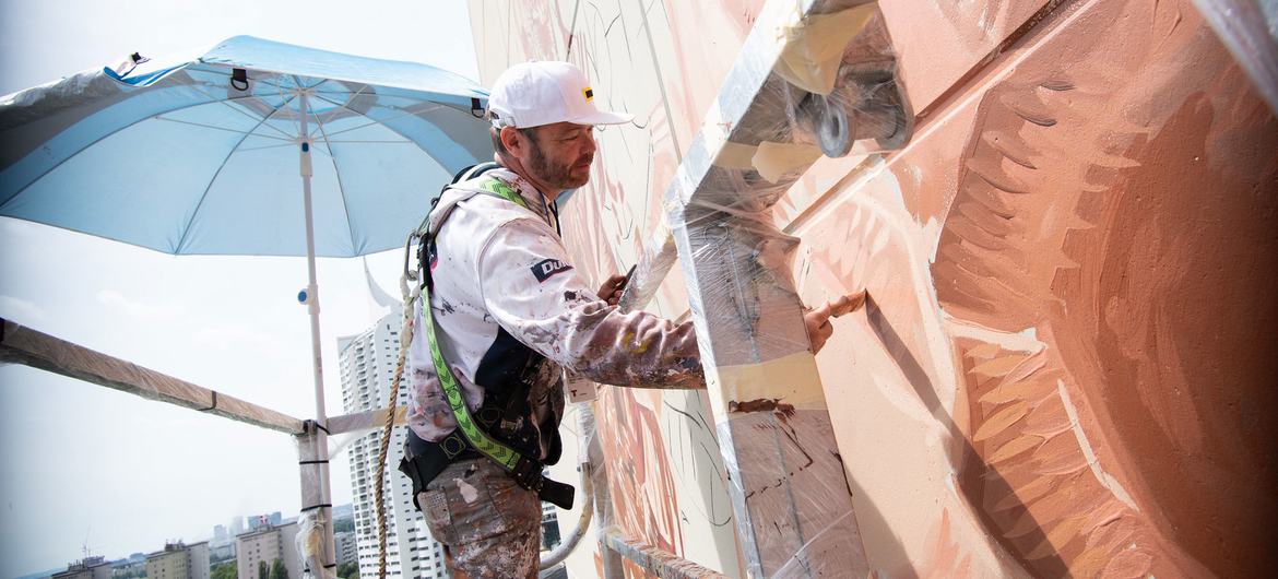 Renowned street artist Fintan Magee of Australia hard at work creating the mural at the Vienna International Centre.