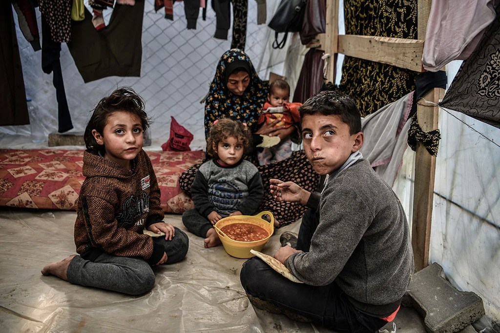 Une famille est assise autour d'un bol de haricots dans sa tente à Rafah, dans le sud de la bande de Gaza.