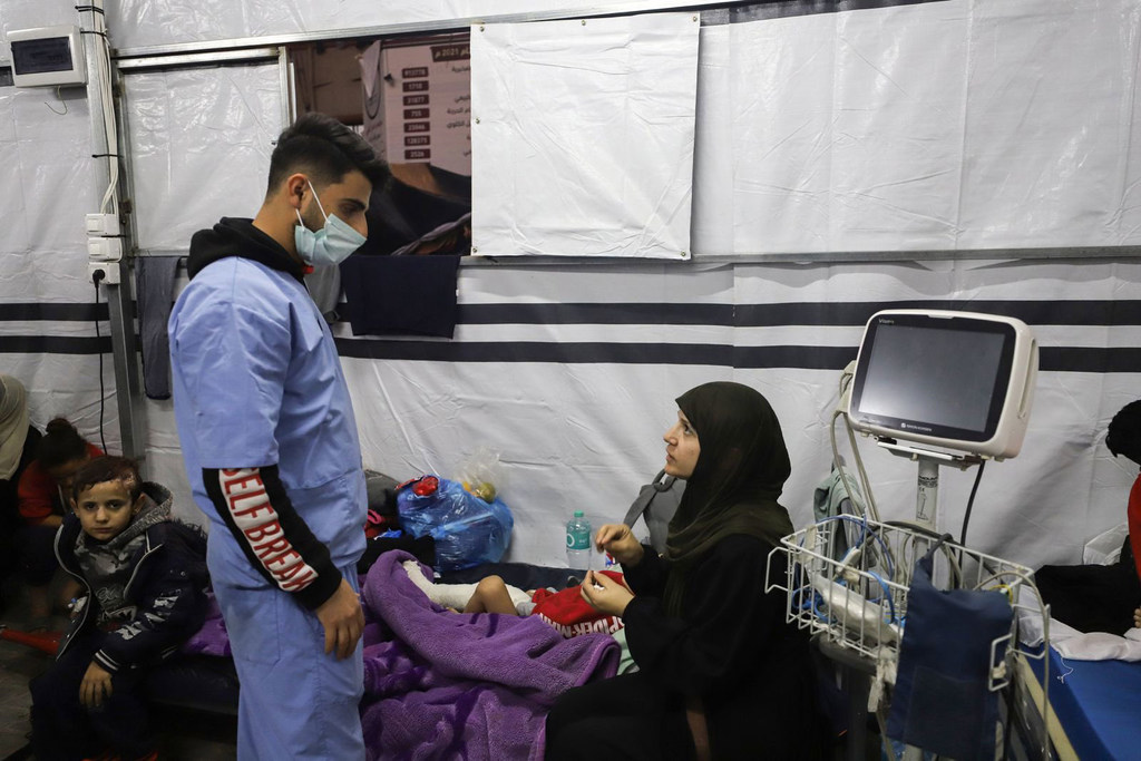 أحد العاملين في مجال الرعاية الصحية يعتني بالأطفال الجرحى في غزة.