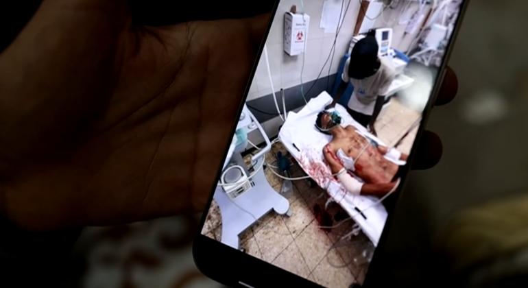  Ibrahim Abu Ashiba, muestra en su teléfono fotos de cuando resultó herido. Espera en un hostapial de la Media Luna Roja a ser evacuado de Gaza