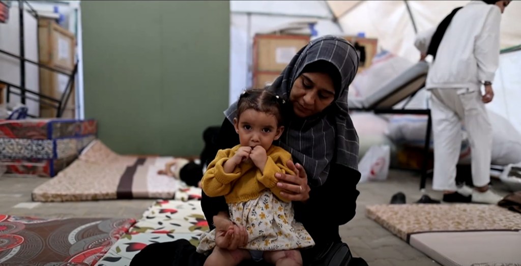 En la fotografía se ve a una madre palestina y a su hijo pequeño dentro de un hospital de campaña en Al Mawasi, Gaza, como paciente evacuado.