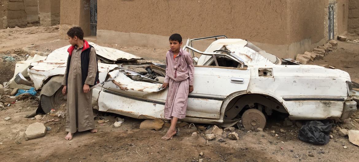 यमन के साआदा में, एक ध्वस्त वाहन के पास खड़े दो लड़के.