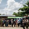 Uma fila de pessoas aguarda a distribuição de alimentos de um caminhão em uma área urbana de Yangon, Myanmar.