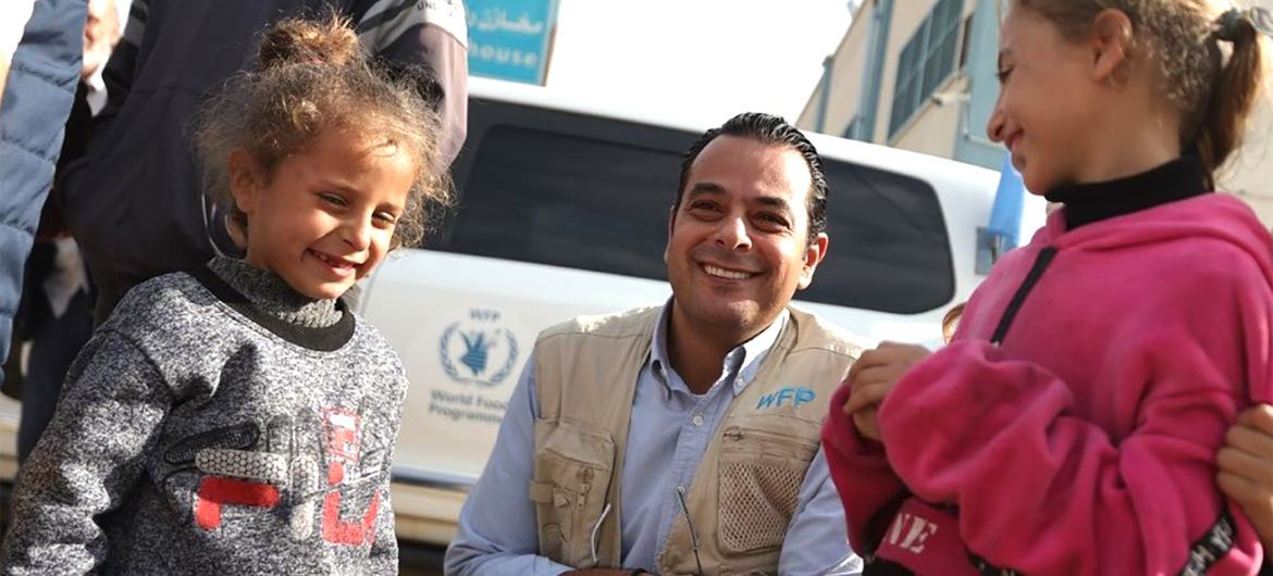 سامر عبد الجابر، مدير تنسيق الطوارئ في WFP، يقف لالتقاط صورة مع فتاتين صغيرتين خلال زيارة ميدانية.