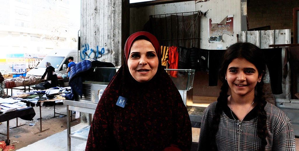 تقف النازحة الفلسطينية أم معاذ حجو وابنتها مرح حجو أمام مبنى قيد الإنشاء في غزة.