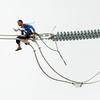 Un ouvrier installe un nouveau cable électrique en haut d'un pylone à Cavite, aux Philippines.