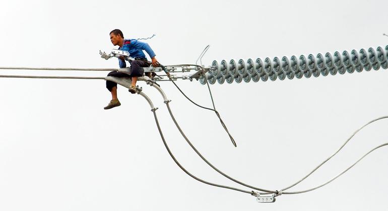 Un trabajador instala un nuevo cable eléctrico en lo alto de una torre en Cavite, Filipinas. (archivo)