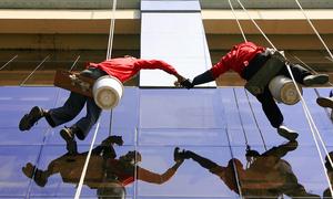 Window cleaners work in Muntinlupa City, Philippines.