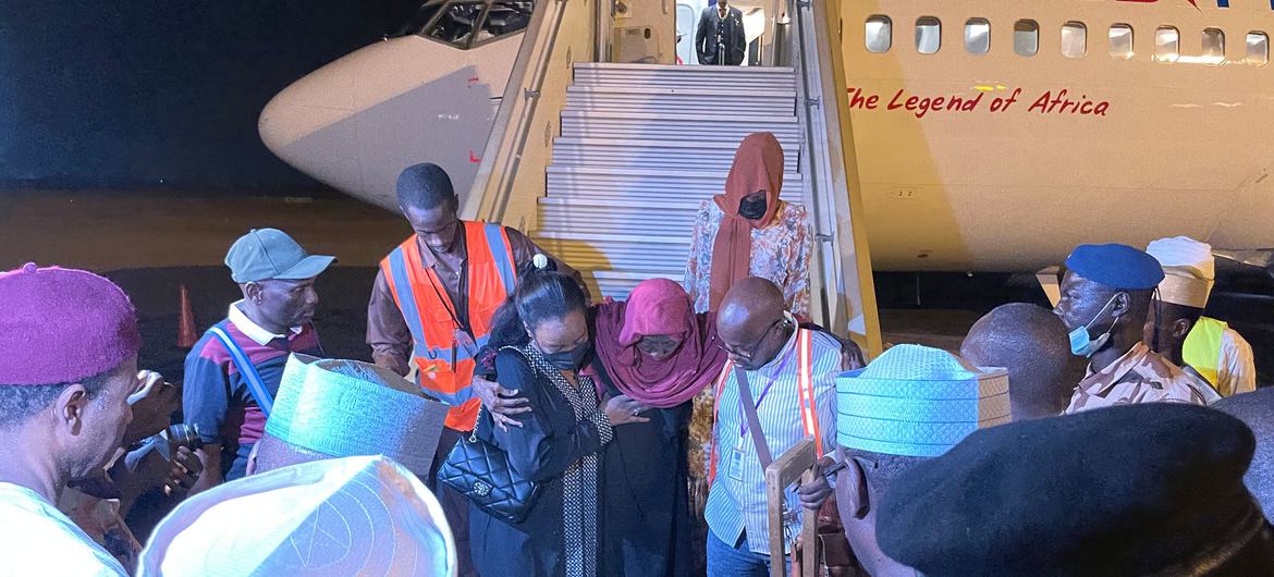 Um passageiro é ajudado a sair de um avião em N'Djamena, Chade, após ser evacuado do Sudão