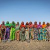 Um grupo de mulheres africanas no Chade está em fila, segurando pás na terra arada.