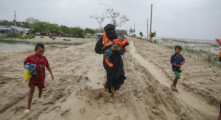 Мать со своими детьми направляется к убежищу перед тем, как циклон обрушится на деревню в Бангладеш.