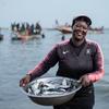 Uma pescadora a caminho de vender o peixe que pescou