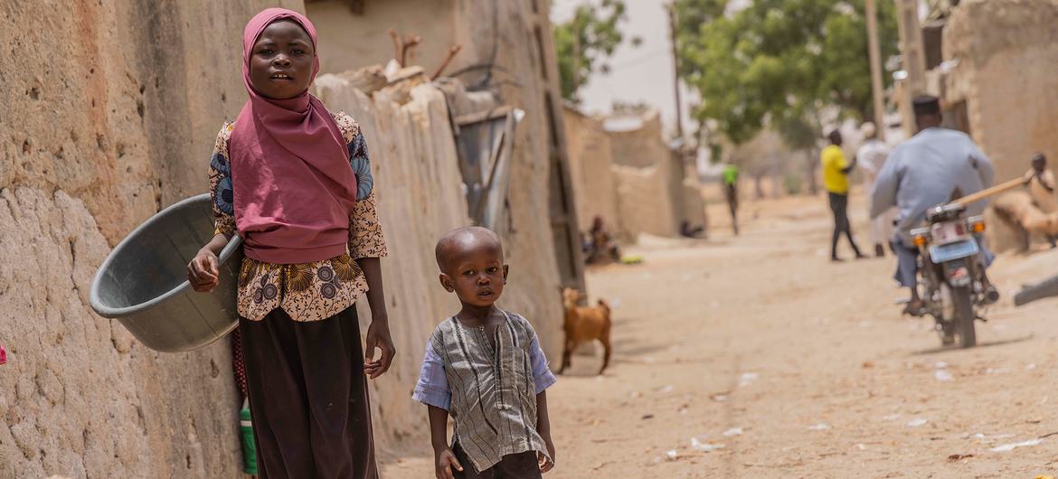 A young girl and her cousin walk through the streets of a village in southern Niger.