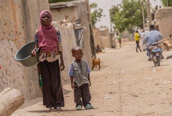 一个女孩和她的表弟走在尼日尔南部一个村庄的街道上。