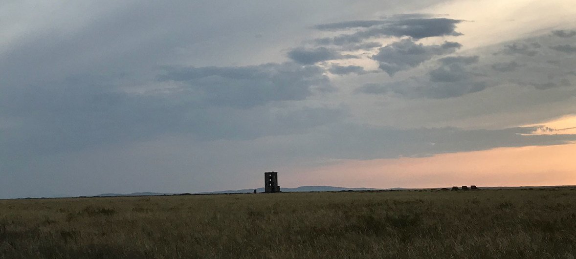A view of the Semipalatinsk Test Site's ground zero monument in the Kazakh steppe under a cloudy sky at sunset.