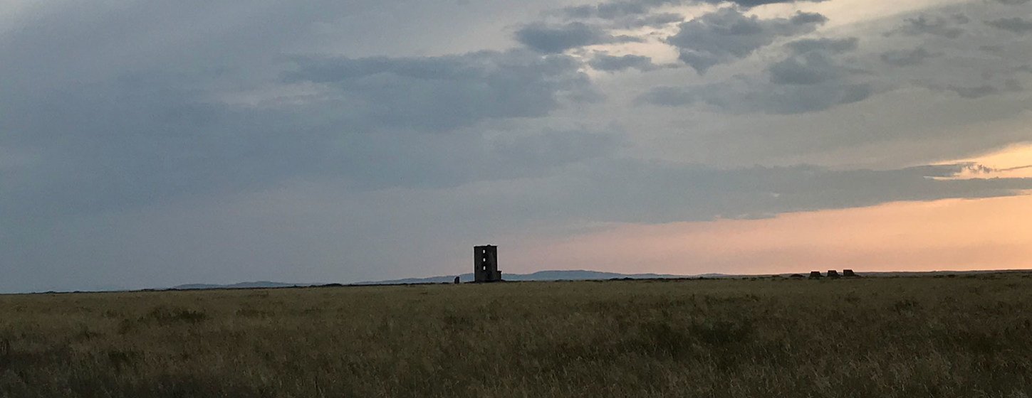 A view of the Semipalatinsk Test Site's ground zero monument in the Kazakh steppe under a cloudy sky at sunset.