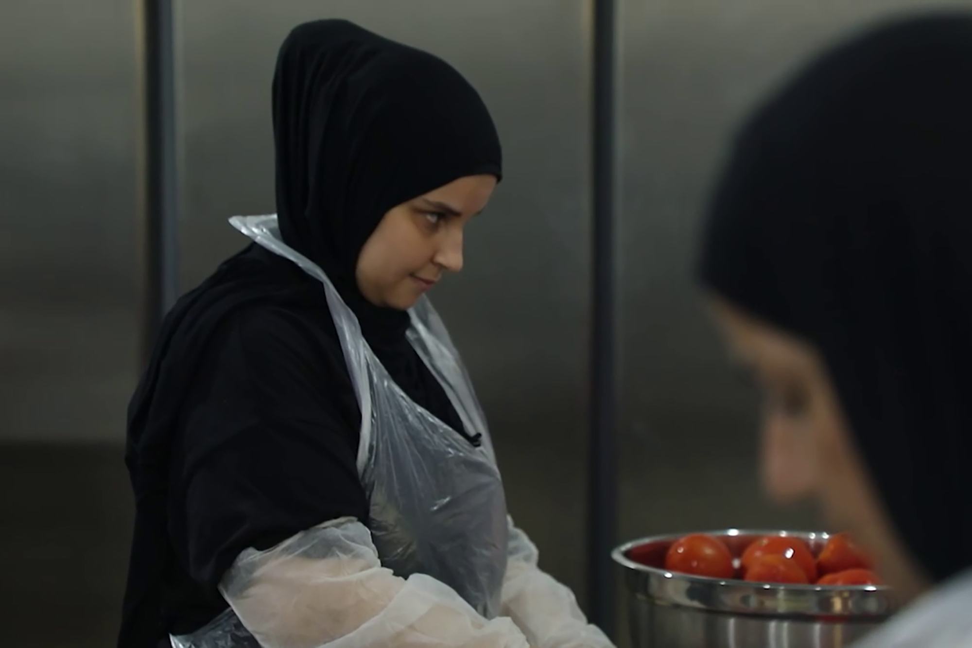 تقوم آية عزو بتقطع البندورة في المطبخ. 
