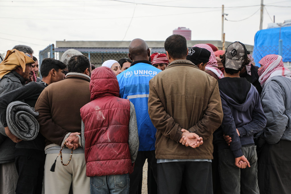 Un employé du HCR fournit des informations à un groupe de personnes déplacées dans le camp d'Areesha, au nord-est de la Syrie...